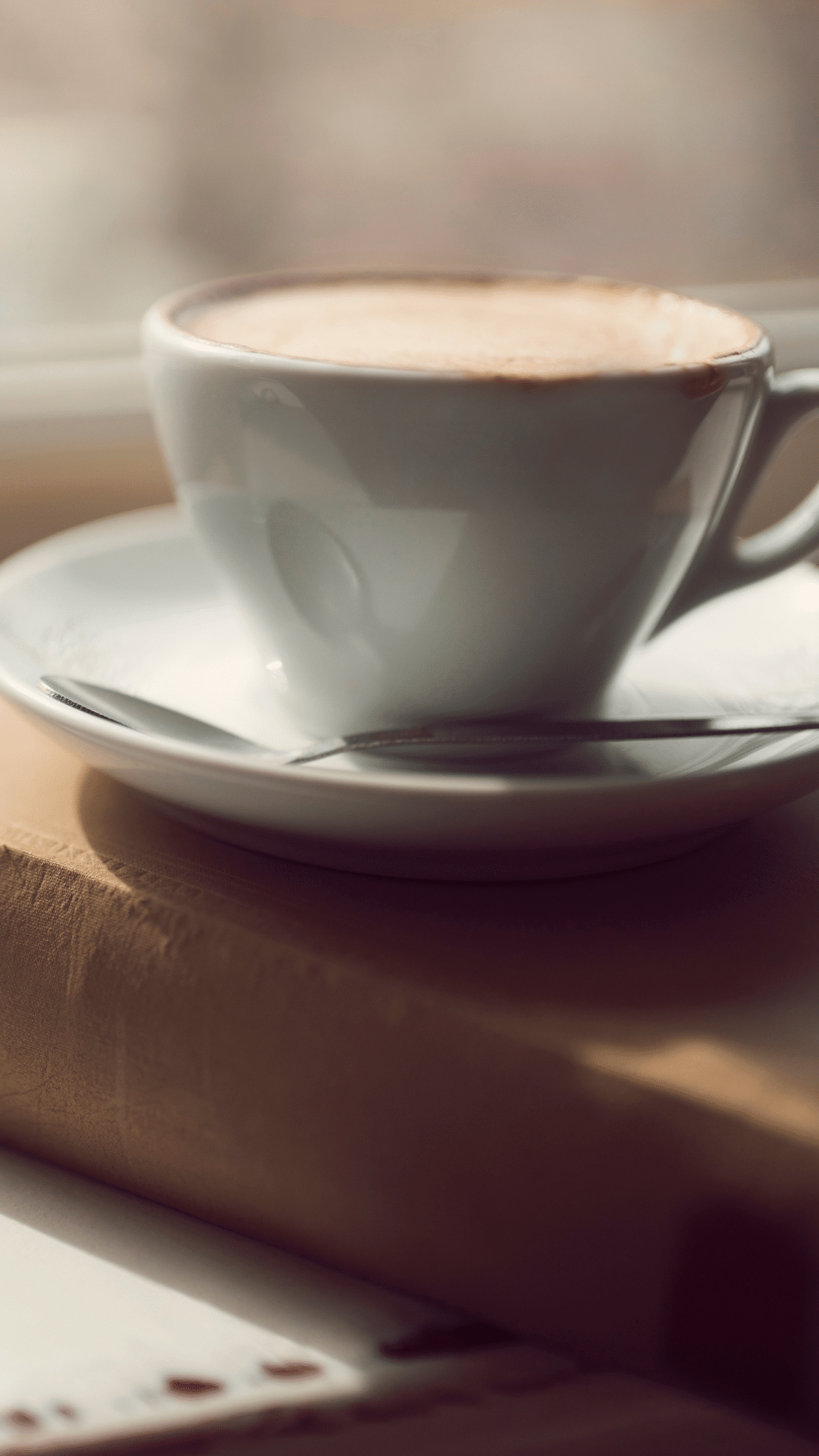 Cappuccino in einer weißen Tasse steht auf einem Buch – Sinnbild für Ruhe und Klarheit.