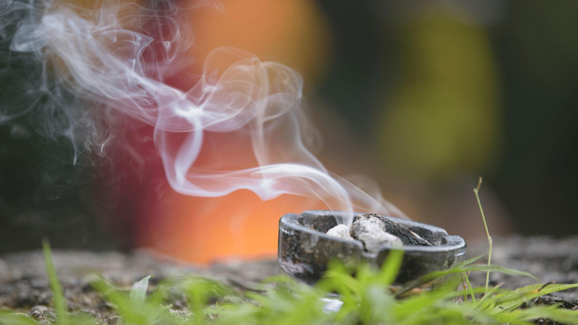 Räucherschale mit aufsteigendem Rauch inmitten von Natur, im Hintergrund warme, unscharfe Lichtfarben. Darstellung von Reinigung, Ritualen und spiritueller Verbindung.