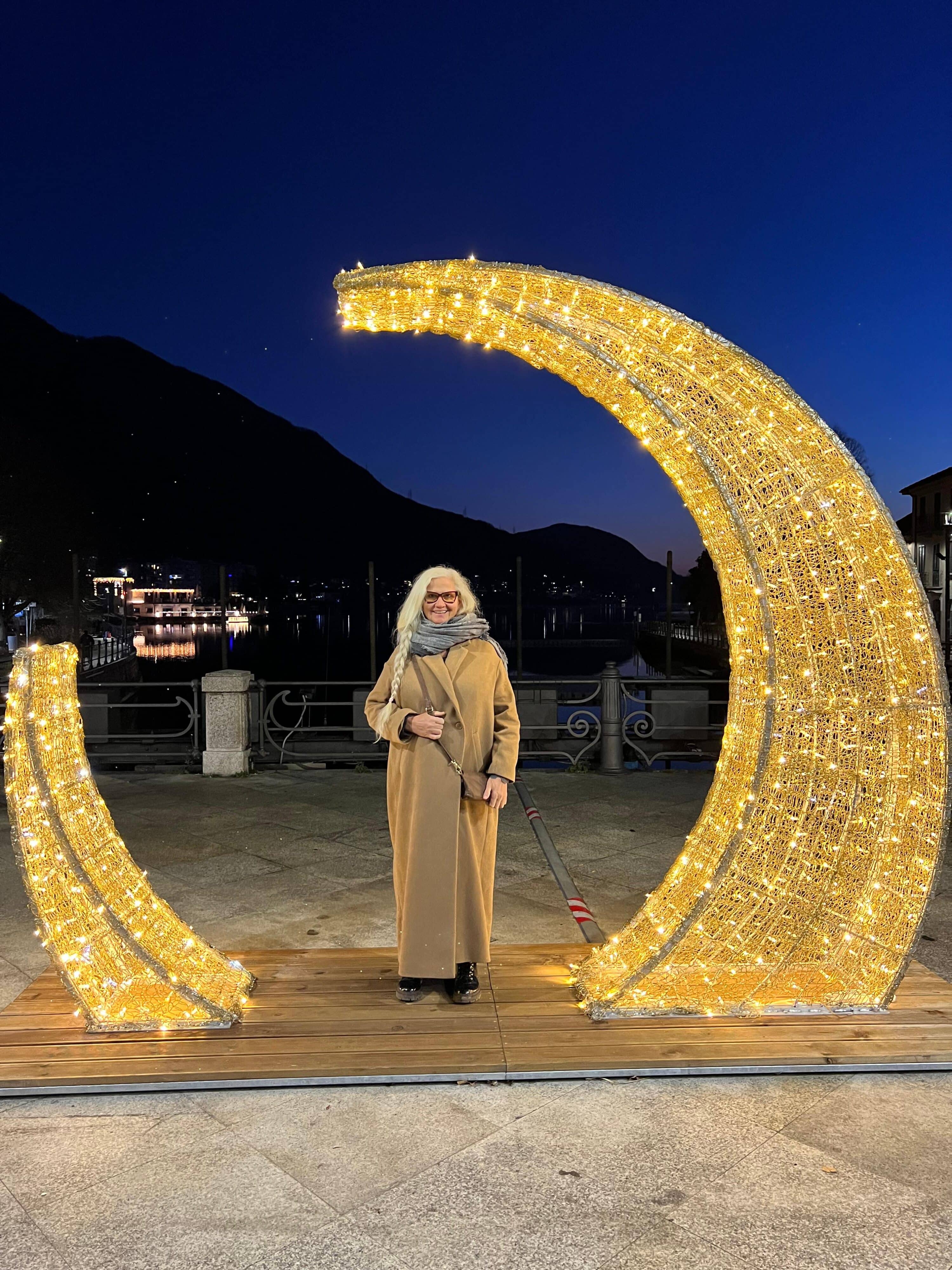 Moti Theresia König steht bei Nacht unter einer Weihnachtsdekoration im Freien.