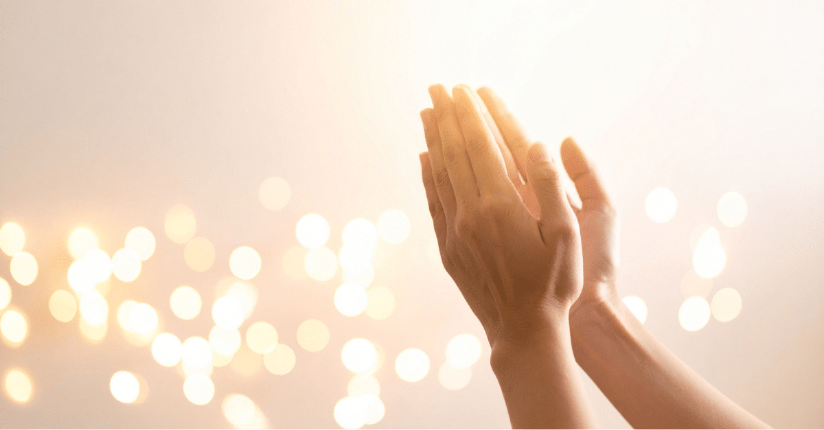 Zwei Hände im warmen, goldenen Licht mit weichen Lichtpunkten im Hintergrund.