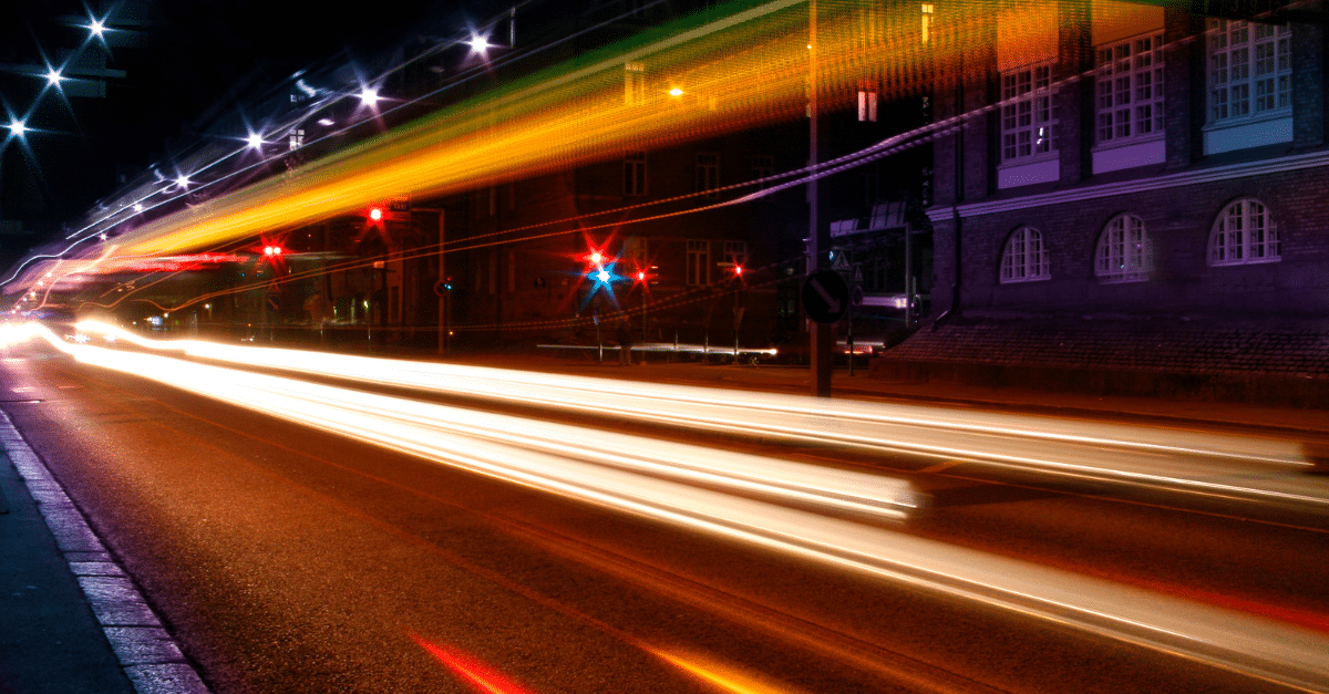 Lichtspuren von Autos auf einer nächtlichen Stadtstraße als Sinnbild für Dauerablenkung und Hektik im Alltag